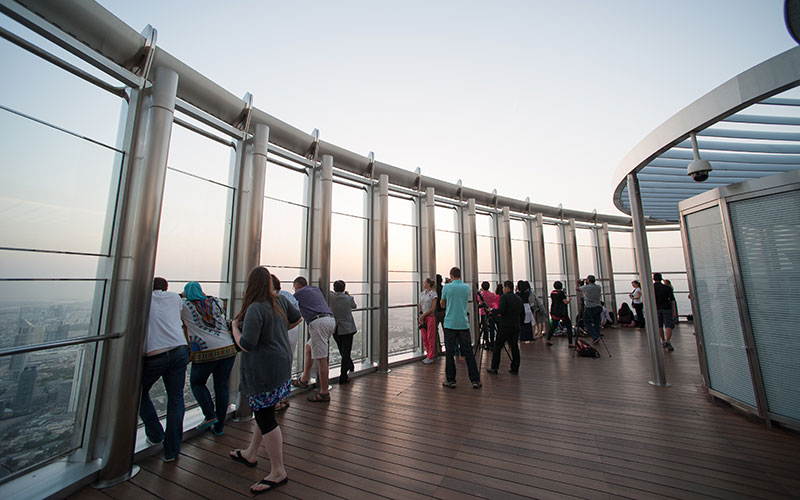 People enjoying a panoramic view of Dubai from the Burj Khalifa observation deck.
