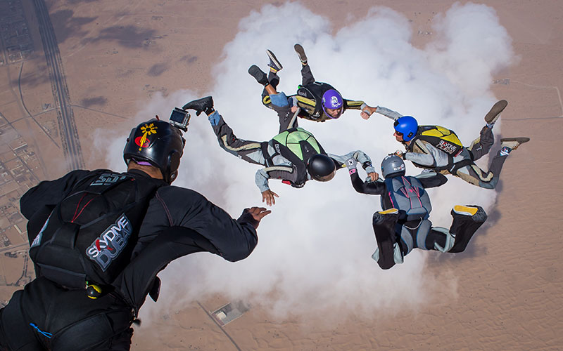 People tandem skydiving over the vast Arabian Desert at Desert Campus, Dubai.