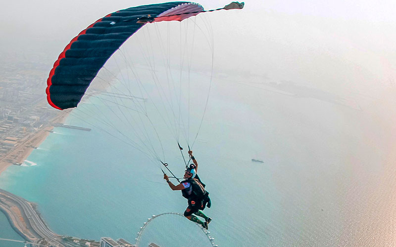 Man gliding with a parachute above Ain Dubai