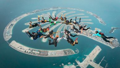 People tandem skydiving above Palm Jumeirah, Dubai.