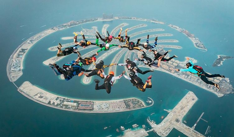 People tandem skydiving above Palm Jumeirah, Dubai.